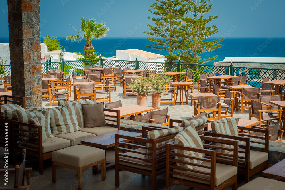 Wooden tables and chairs in seaside Greek restaurant