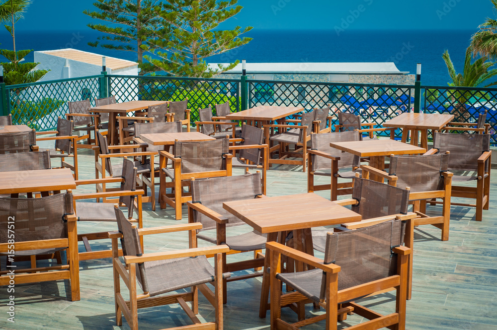Wooden tables and chairs in seaside Greek restaurant