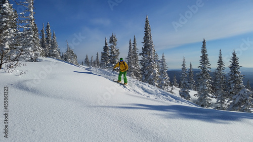 Snowboarding rider in mountains with snow, blue sky winter landscape, Russia