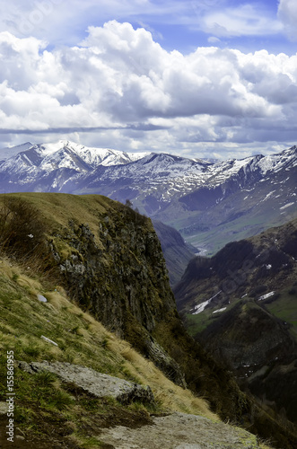 Beautiful scenic green summer landscape with snowy mountain peak tops on blue sky background