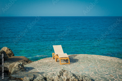 Obraz na płótnie Sunbed on the rocks next to turquoise sea w salonie