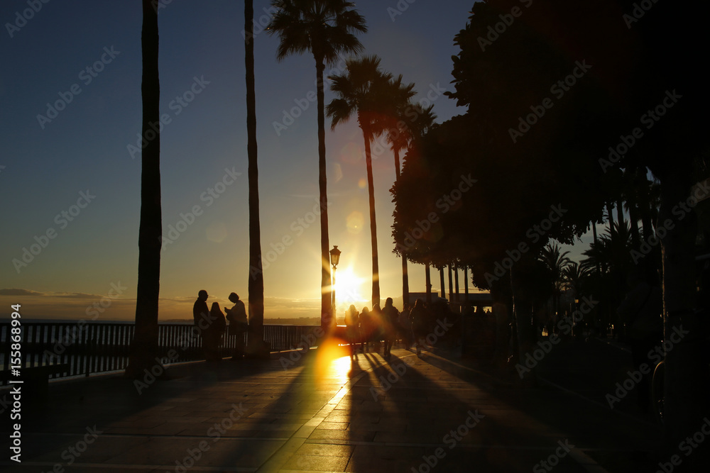 seaside boulevard in Marbella, Spain with colorful lens flares during sunset