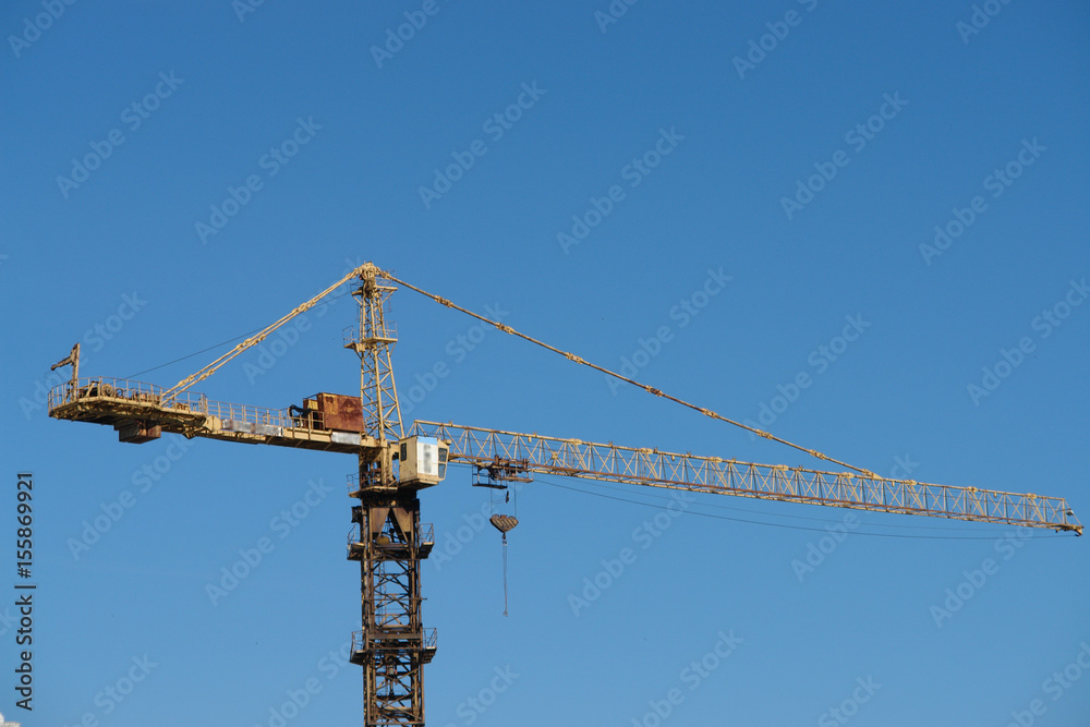 Tower crane on construction site against blue sky. Tower crane on construction site against blue sky.