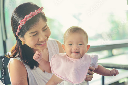 Asian happy mom holding happy baby girl. Vintage effects, soft focus and soft light