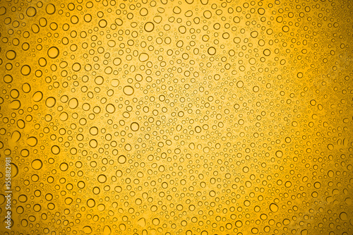 Water drops on yellow glass  Rain droplets on glass background.