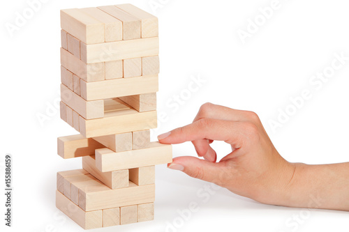 Obraz na plátně The tower from wooden blocks and man's hand take one block