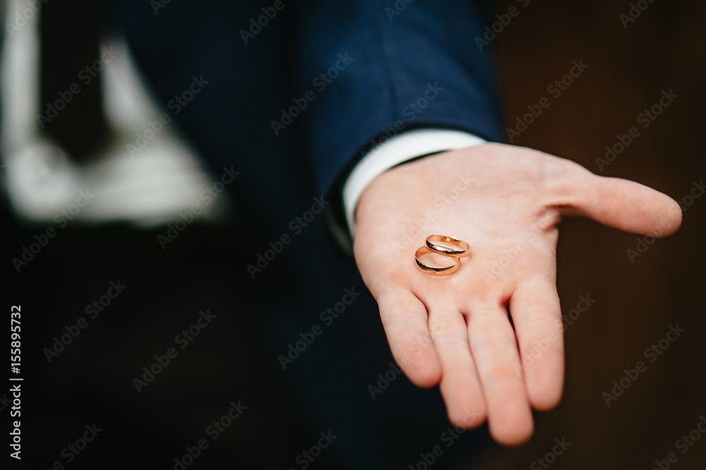 The groom holds wedding rings
