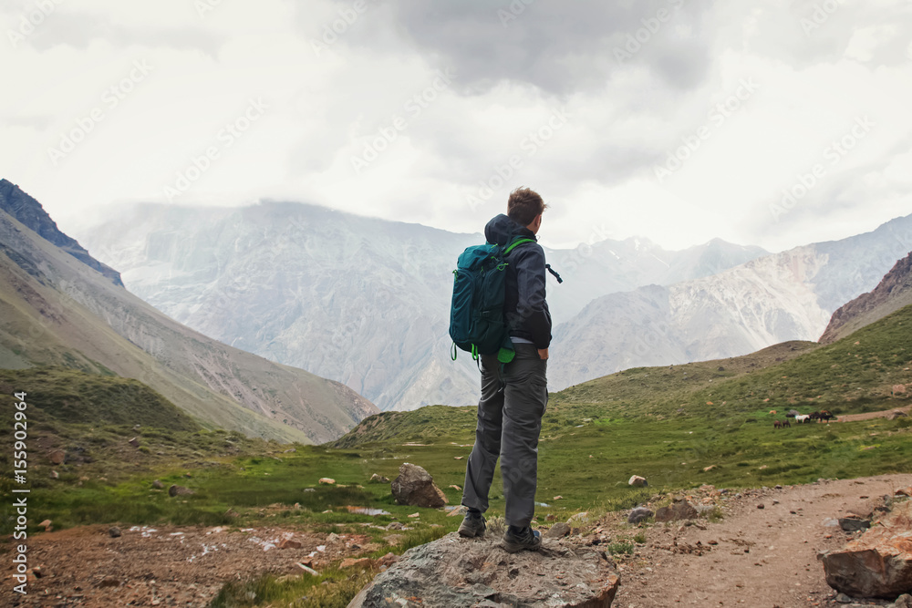 Young man with backpack hiking in mountains