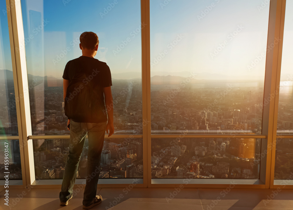 Fototapeta premium Man looking over the big city from the viewpoint at sunset time.