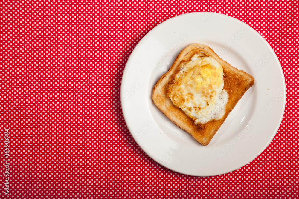 Toast and egg on a plate on a red table Toast and egg on a plate on a red table