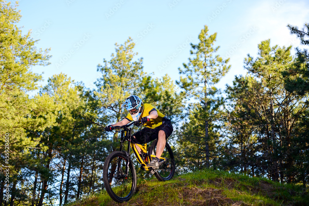 Professional Cyclist in Yellow T-shirt and Helmet Riding the Bike Down Hill in Forest. Extreme Sport Concept. Professional Cyclist in Yellow T-shirt and Helmet Riding the Bike Down Hill in Forest. Extreme Sport Concept.