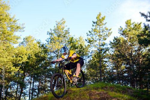 Professional Cyclist in Yellow T-shirt and Helmet Riding the Bike Down Hill in Forest. Extreme Sport Concept.