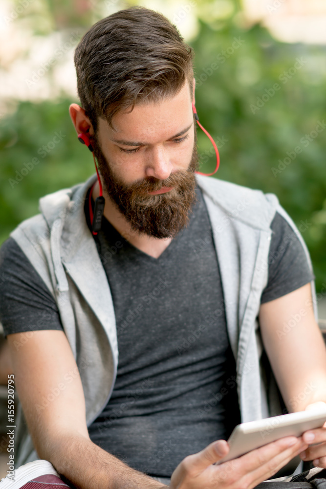 Cute guy with beard and earphones watching videos on a digitale e-reader tablet Cute guy with beard and earphones watching videos on a digitale e-reader tablet
