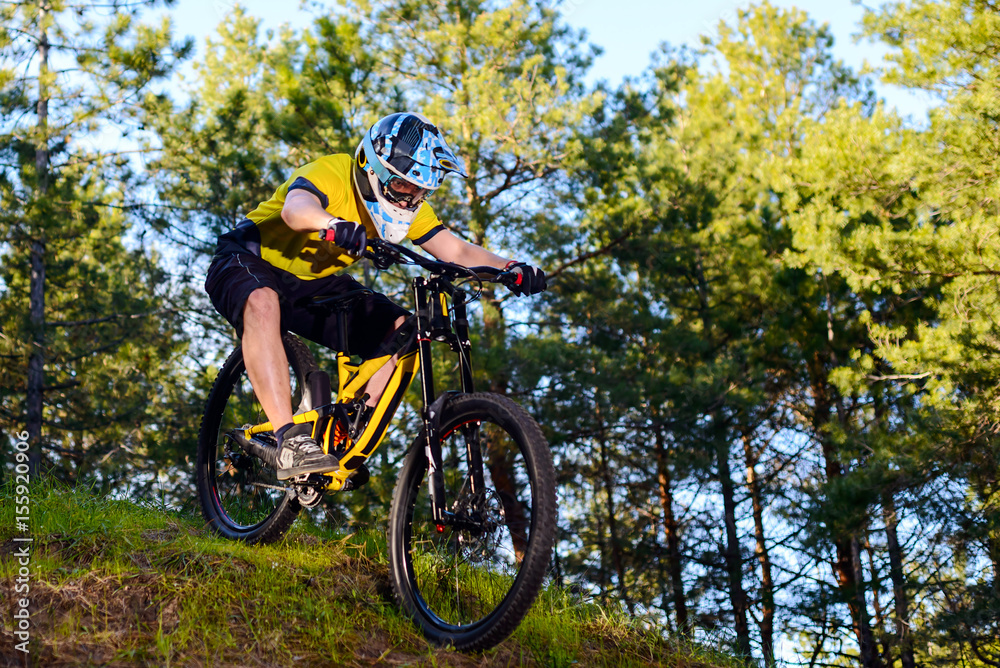 Professional Cyclist in Yellow T-shirt and Helmet Riding the Bike Down Hill in Forest. Extreme Sport Concept.