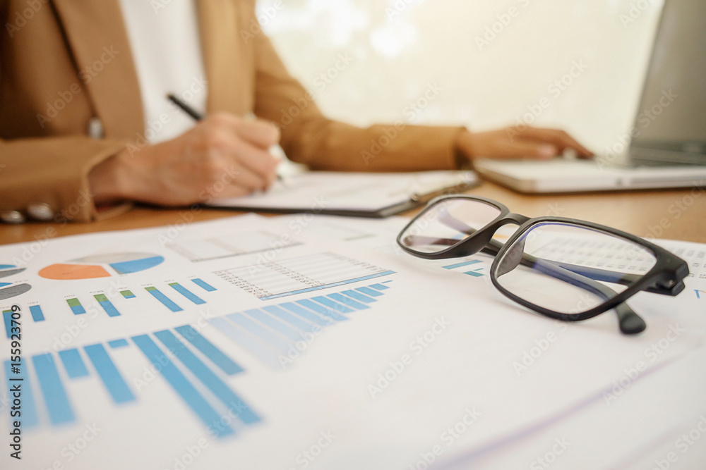 Business concept with copy space. Office desk table with glasses focus and analysis chart computer notebook cup of coffee on desk.Vintage tone Retro filter effect.Selective focus. Business concept with copy space. Office desk table with glasses focus and analysis chart computer notebook cup of coffee on desk.Vintage tone Retro filter effect.Selective focus.