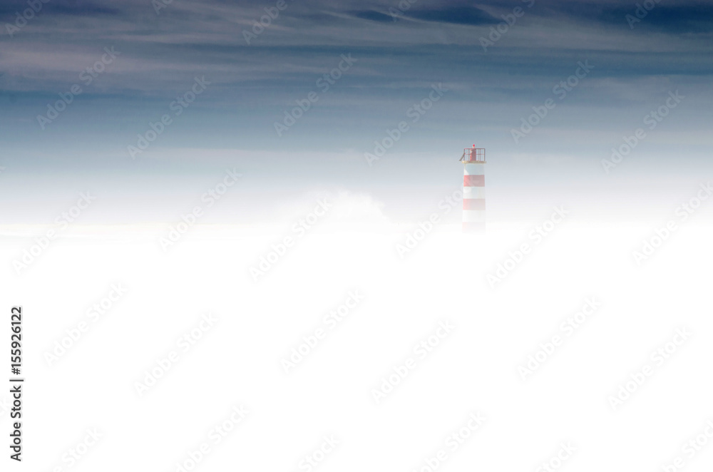 Sylwetka latarni morskiej wyłaniająca się spoza gęstej mgły. Granatowe niebo, gęsta mleczna mgła, drobna sylwetka latarni po prawej stronie.  - obrazy, fototapety, plakaty 