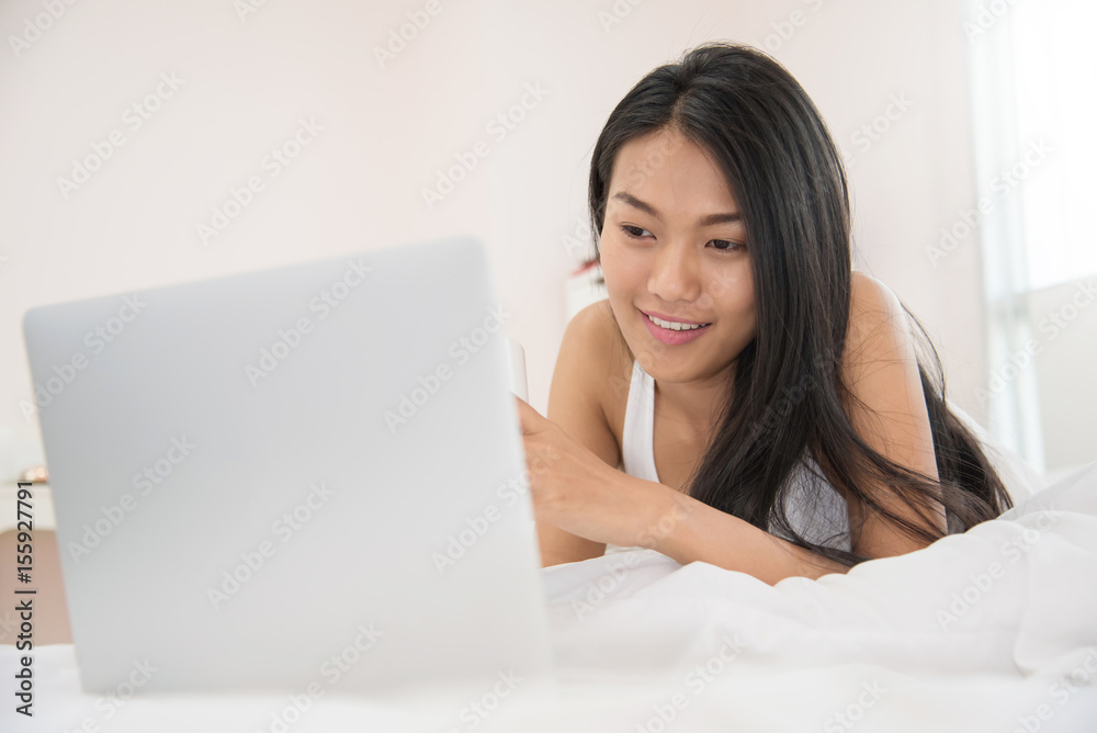 Happiness Asian girl smiling and using on laptop on her bed. Happiness Asian girl smiling and using on laptop on her bed.