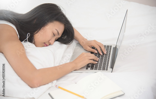 Asian girl sleeping with laptop on her bed.