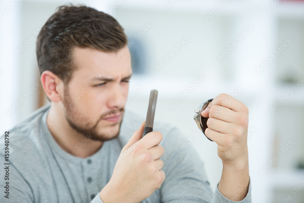 young man looking at watch through magnifying glass young man looking at watch through magnifying glass