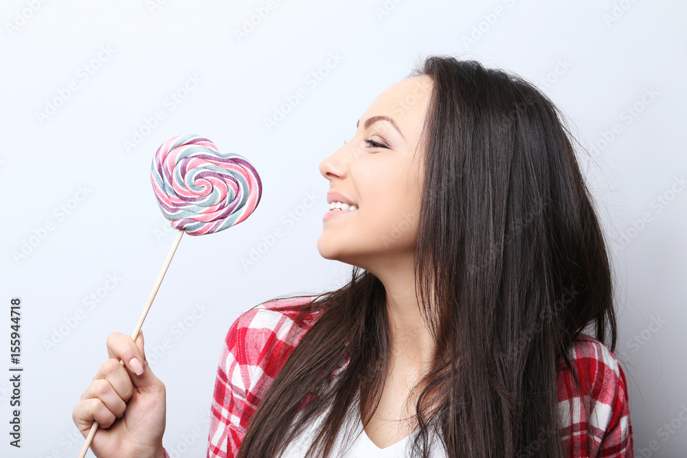 Young woman with lollipop on grey background