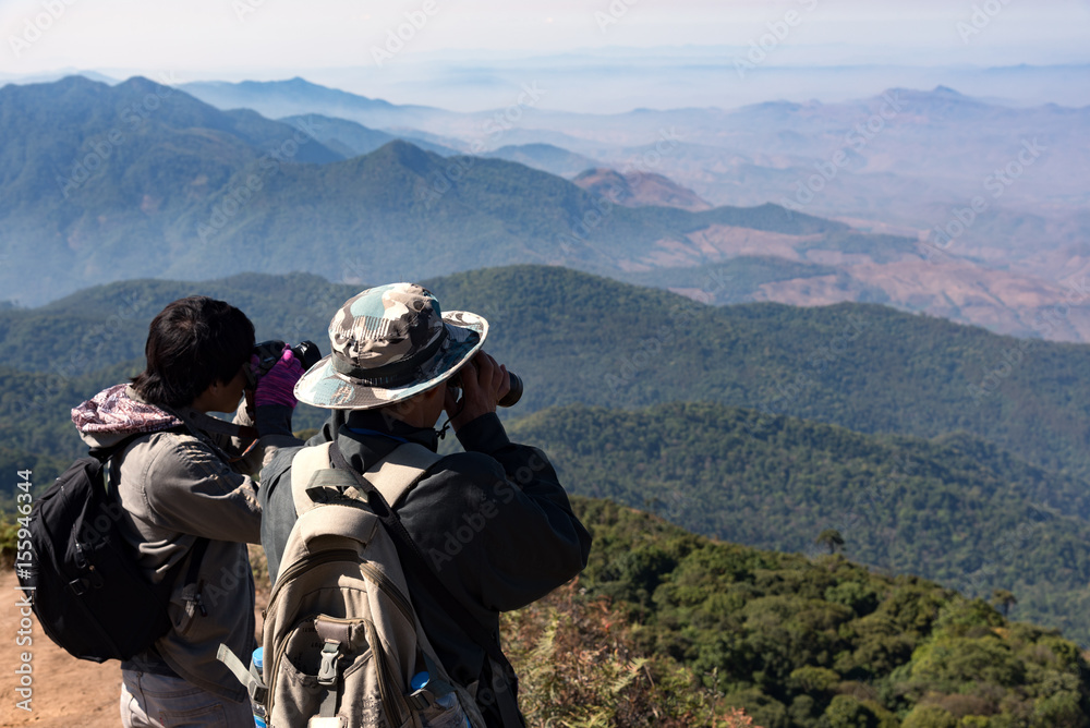travel hiker man is using binoculars to looking nature on mountain