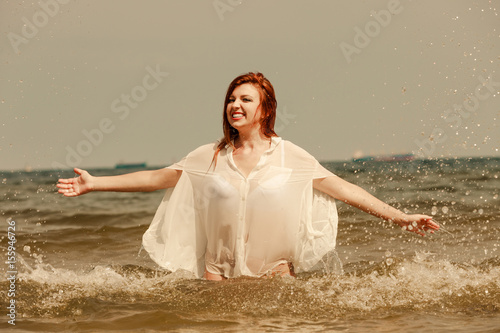 Redhead woman playing in water during summertime