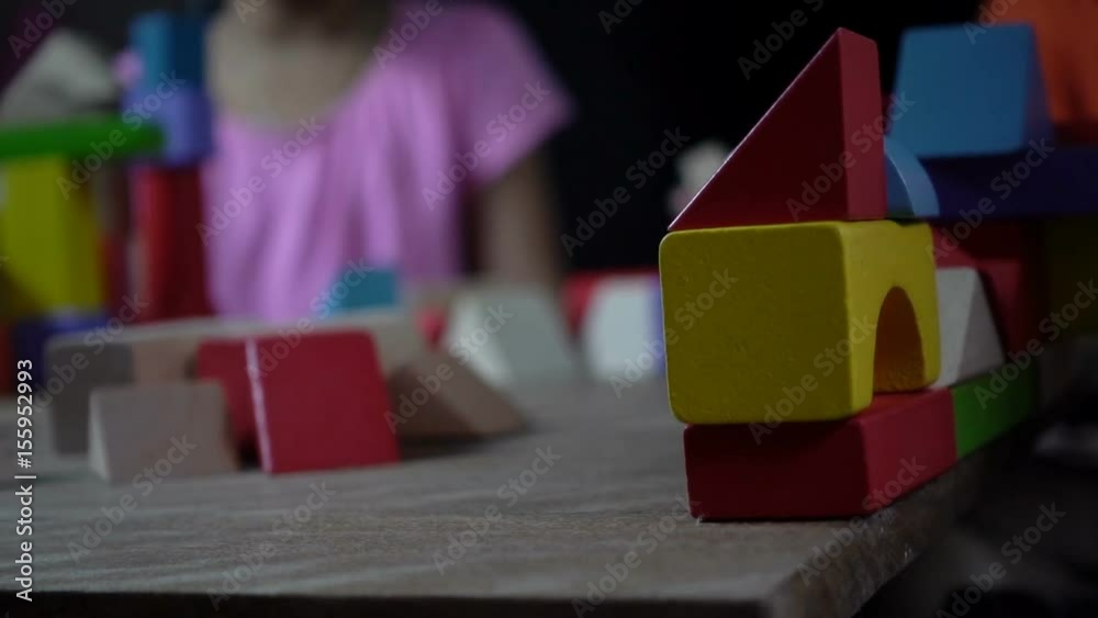Little asian girl playing with wood blocks in dark room, slow motion shot. Stock ビデオ | Adobe Stock