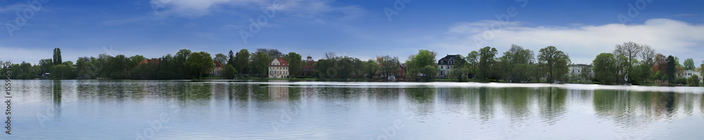Panorama of a countryside landscape in clear weather with a large lake, trees and houses. Panorama of the Heiliger lake in Potsdam, Germany.