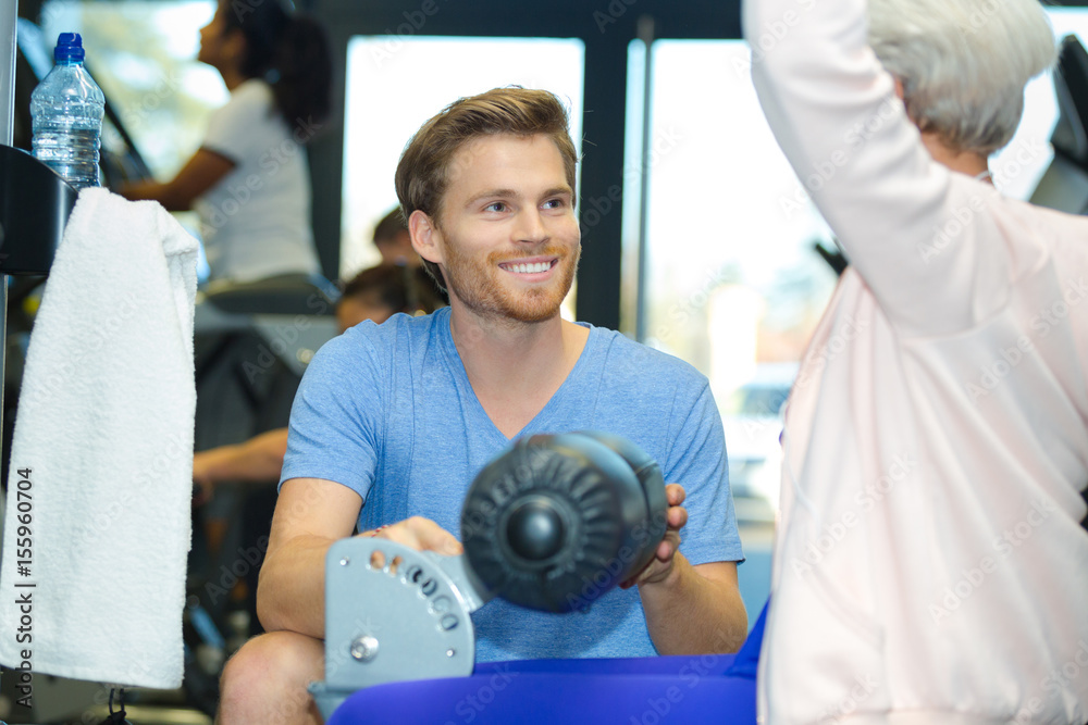 coach explaining exercise equipment to senior woman