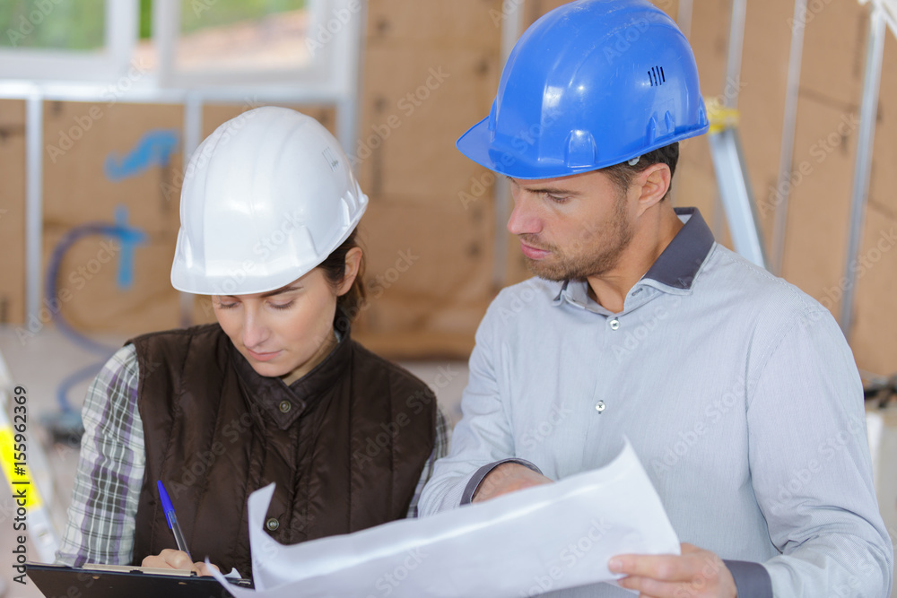 Two people in hardhats on building site Two people in hardhats on building site