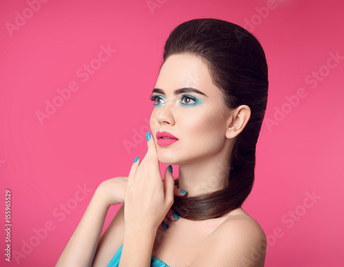 Beauty makeup. Fashion girl portrait. Blue manicured nails. Glamour young woman brunette with eye shadow visage and matte lipstick isolated over pink background.