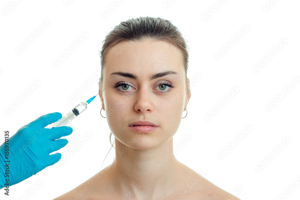 cosmetologist makes injection syringe on the face of a young beautiful girl who looks straight close-up cosmetologist makes injection syringe on the face of a young beautiful girl who looks straight close-up