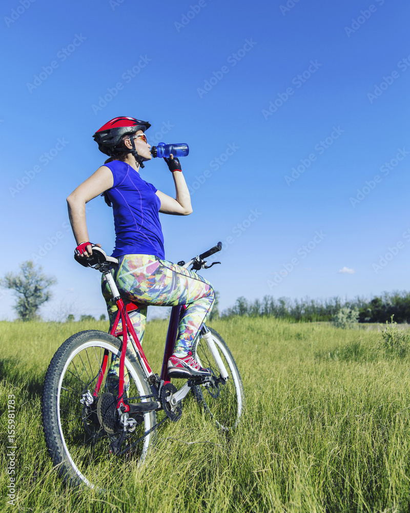 Attractive, healthy woman drinks from her water bottle on mountain bike. active outdoor lifestyle concept. Attractive, healthy woman drinks from her water bottle on mountain bike. active outdoor lifestyle concept.