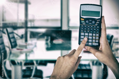 Composite image of hands of businesswoman using calculator photo