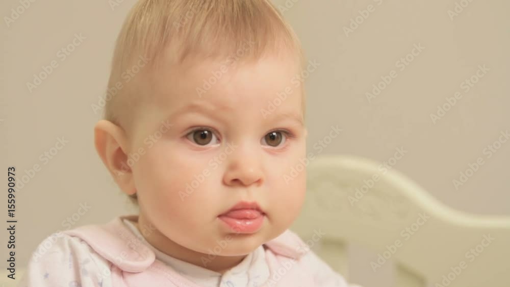 A little girl, aged one year carefully and emotionally looks at the screen close up A little girl, aged one year carefully and emotionally looks at the screen close up
