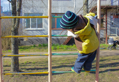 little boy, in kindergarten, on the Playground, climbs on the Swedish ladder. The child climbs on the Playground.. © Tamara