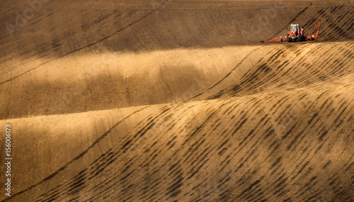 Rural Scenic Landscape.Modern Red Tractor Plowing And Spraying On Field. Small Tractor Working On A Colorful Spring Field.Agriculture Tractor Creating Abstract Brown Background Texture.Czech Republic