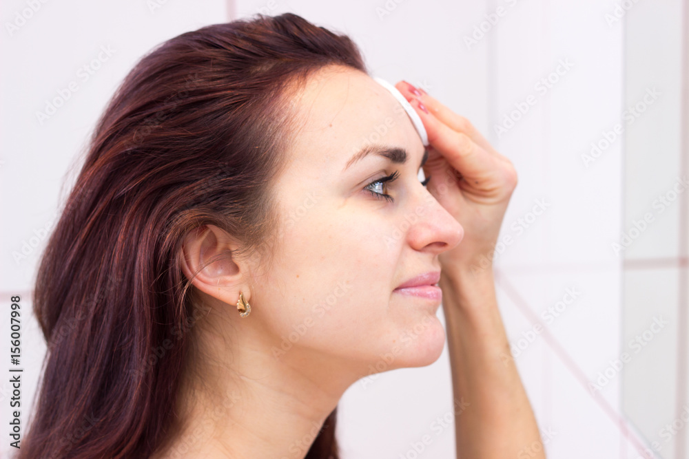 Young woman removing makeup in bathroom Young woman removing makeup in bathroom