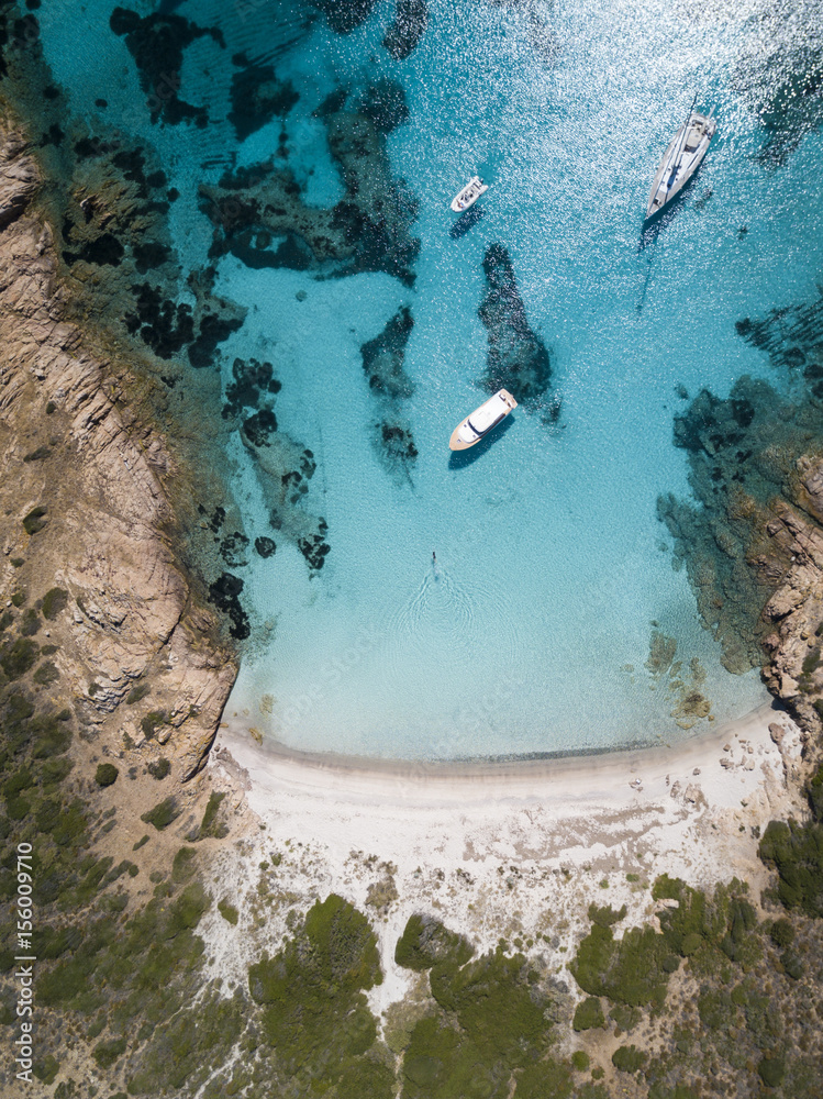 Aerial view of a boat in front of the Mortorio island in Sardinia. Amazing beach with a turquoise and transparent sea. Emerald Coast, Sardinia, Italy.
