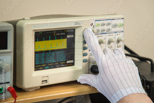 Fotografija Modern oscilloscope, man's hand adjusting wave signals, closeup
