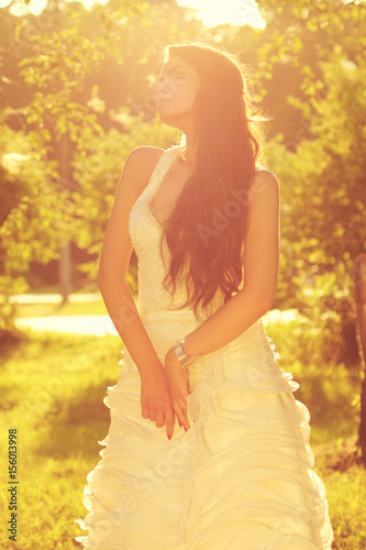 tender romantic portrait of young beautiful bride in white dress posing in sunlight at nature. warm colors