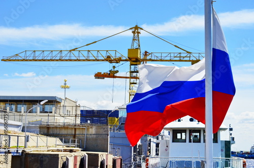 Waving Russian flag on the background of the port and the crane