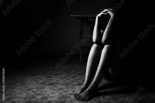 a woman sitting on ground with arm around lower head, sexual violence , sexual abuse, human trafficking concept