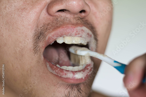 man brushing teeth with herb toothpaste in morning