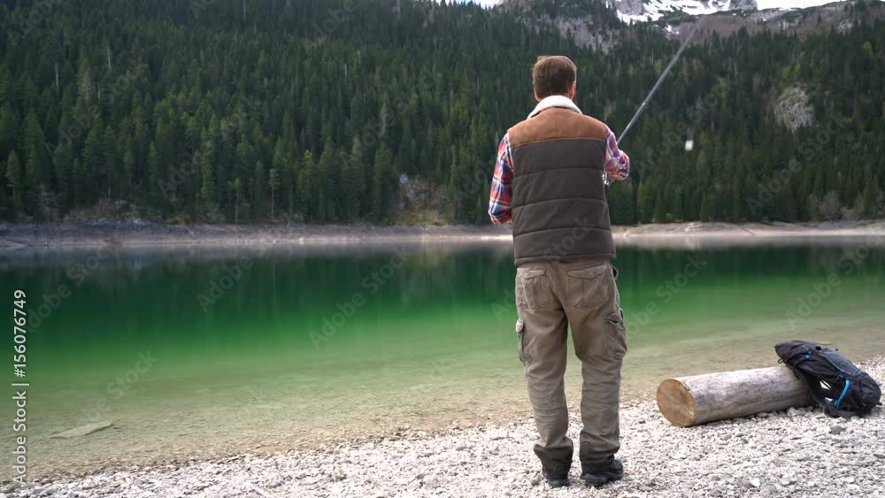 young man cast a spinning on the shores of scenic Lake young man cast a spinning on the shores of scenic Lake