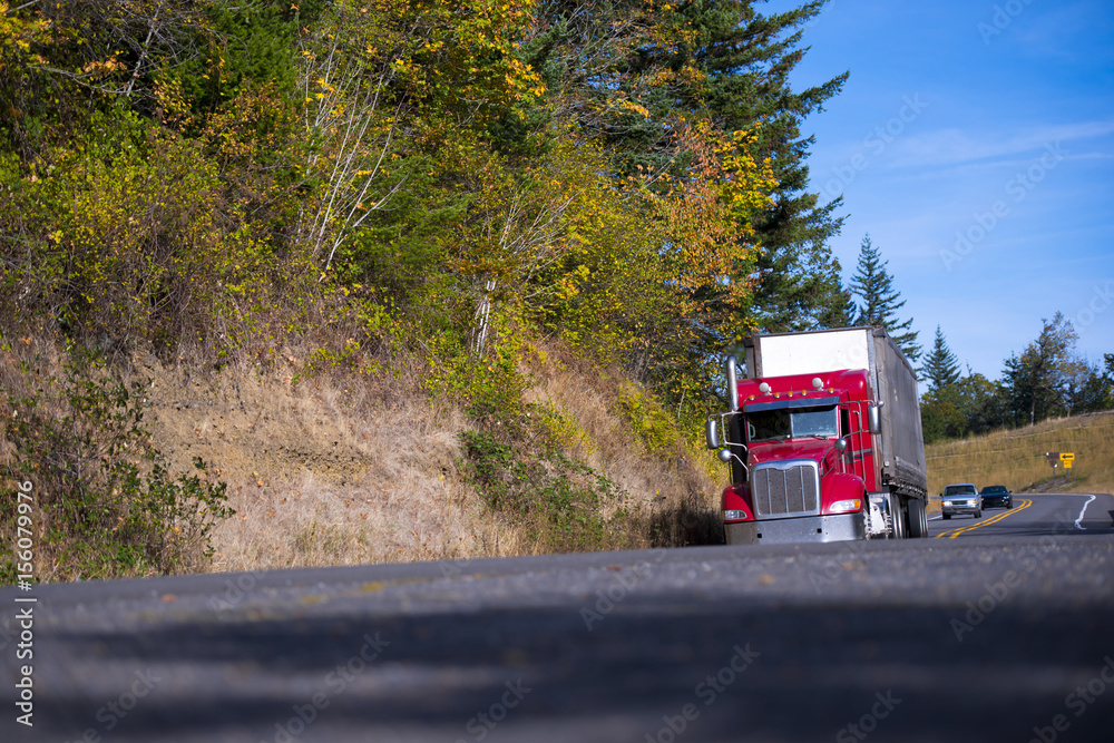 Classic modern red semi truck dry van trailer on autumn road