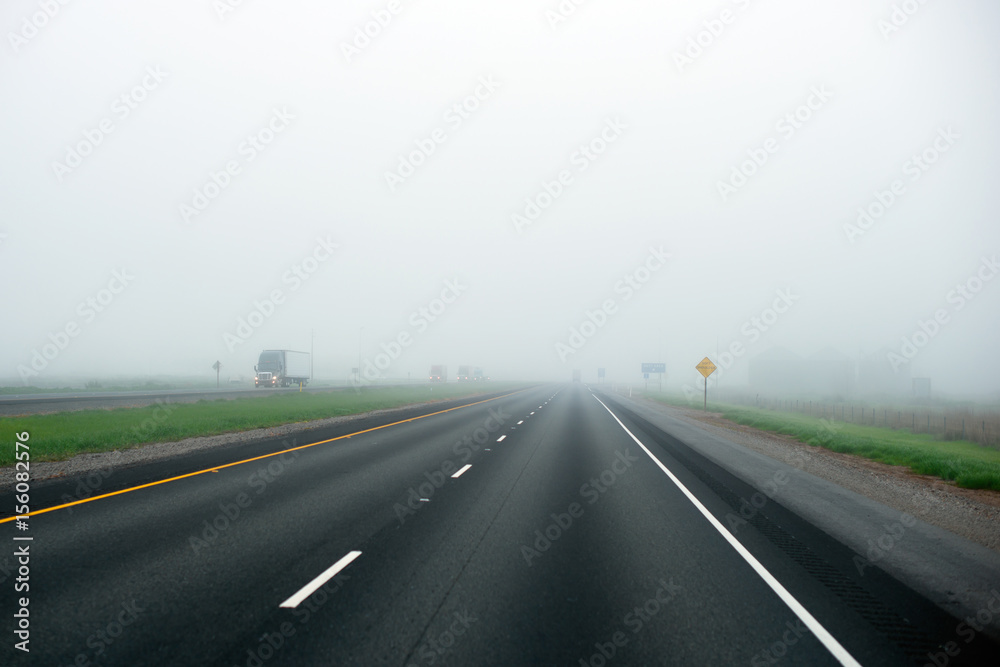 Foggy highway with dividing strip marking of green grass and truck with lights on Foggy highway with dividing strip marking of green grass and truck with lights on