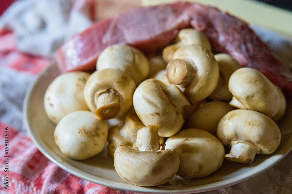 Fresh white mushrooms and raw meat on plate Fresh white mushrooms and raw meat on plate