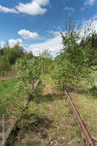 Abandoned railway in green landscape.