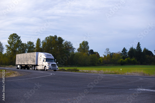 Modern long haul semi truck tarp trailer on straight highway